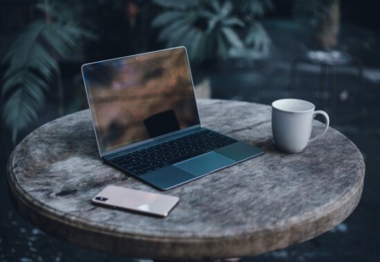 木のテーブルのノートPCとコーヒーの写真